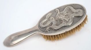A Chinese silver backed hair brush: monogrammed, decorated with a dragon, 23cm. long.