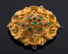 A Victorian gold, emerald and diamond-set oval brooch: of open, scroll work design,