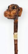 A carved hickory walking cane:, the handle in the form of a glum looking monkey,