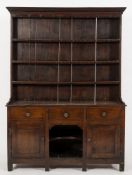 An early 19th Century oak dresser:, the shelved superstructure with a moulded cornice,