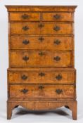 An antique walnut veneer tallboy: in two parts, the upper part with a moulded cornice,