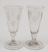 A pair of ale glasses: the trumpet shaped bowl engraved with hops and barley on a short knopped