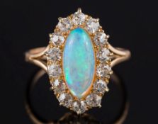 A gold, opal and diamond mounted oval cluster ring: with central oval opal 13.5mm. long x 5.8mm.