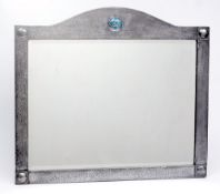 An Arts and Crafts wall mirror:, the arch topped pewter frame with central enamelled roundel,