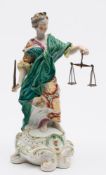 A Derby figure of Justice: wearing a green robe and richly patterned dress,