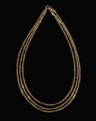 A gold triple strand necklace: with bolt ring clasp stamped '15c', approximately 23gms gross weight.