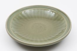 A Chinese longquan celadon dish:  the centre decorated with a roundel of scrolling foliage inside a