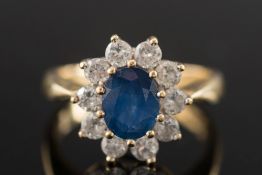 An 18ct gold, sapphire and diamond oval cluster ring:, the oval sapphire between circular,