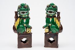 A pair of Chinese 'egg and spinach' glazed Fu-dog incense holders: on raised pierced bases,