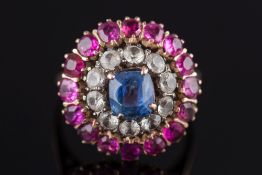 A Ceylon sapphire and ruby mounted circular cluster ring: with central cushion-shaped sapphire