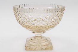 A cut glass circular bowl: with fluted rim and fret cut body on a square star cut base,
