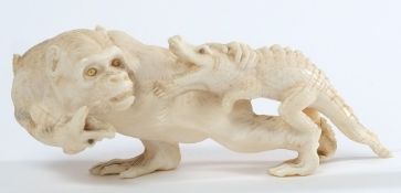 A Japanese carved ivory okimono: of a monkey with mother of pearl eyes holding two young crocodiles,