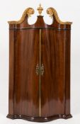 A George III mahogany and carved giltwood serpentine fronted hanging corner cupboard:,