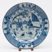 A Chinese blue and white dish: painted with two ladies seated on a terrace outside a building,