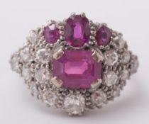 A ruby and diamond circular cluster ring:, the central, rectangular ruby below three smaller,