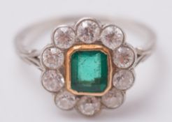 An emerald and diamond oval cluster ring:, the rectangular emerald within a surround of circular,