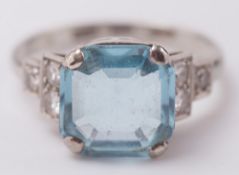 An aquamarine and diamond ring:, the square-cut aquamarine between diamond three stone shoulders,