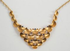 An 18ct gold, sapphire and diamond bib necklace: with a cluster of textured concave crescent discs,