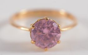 A pink gem set single stone ring: on yellow metal shank.
