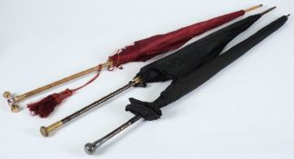 An Edwardian silk parasol with gold and enamelled handle and two other decorative parasols: (3)