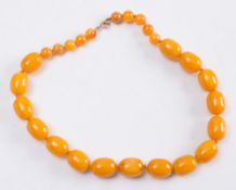 An amber coloured, graduated bead single string necklace:.