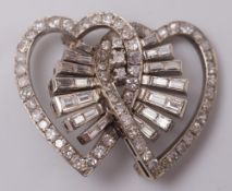 A diamond double heart brooch: with central baguette-cut diamond spray cluster, 8.5gms gross weight.