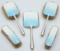 A George V five piece silver and blue enamel dressing table set,