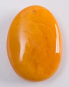 An oval amber drop pendant of egg yolk colour, 55mm long x 40 mm wide, 22.5gms gross weight:.