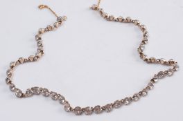 A cushion shaped, colourless paste-set necklace:, the single row of pastes within a yellow metal,