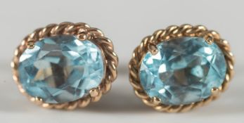 A pair of oval blue topaz, single stone ear studs:.