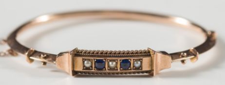 A Victorian gold, sapphire and seed pearl hinged bangle:, with fitted, blue velvet case.