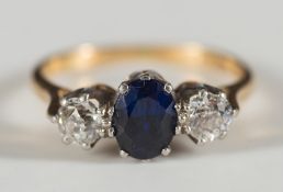 An 18ct gold, sapphire and diamond three stone ring:, the oval sapphire between two circular,