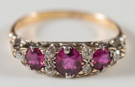 An 18ct gold, graduated ruby and diamond nine stone ring: in scroll pierced setting.