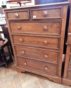 A modern hardwood chest of two short and four long graduated drawers with turned wooden handles,