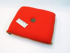 A Prince of Wales Investiture pillow in orange wool trimmed with gold braid and a metal insignia