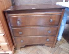 An oak chest of drawers with floral and scroll brass handles, on bracket supports,