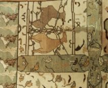 A wool carpet in green and beige depicting deer and other animals, on a cream ground,