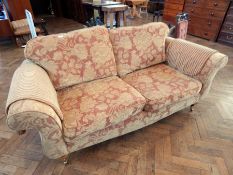 A two seater sofa with floral russet upholstery, loose cushion back and seats, with arm protectors,