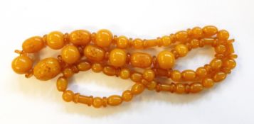 Carved and polished yellow amber coloured bead necklace having graduated oval carved beads with