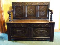 An oak settle with lunette and rose three-panelled back,