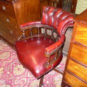 A mid C20th mahogany swivel captain chairs upholstered in red button leather raised on castors