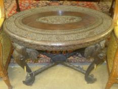 A C20th Indian carved hardwood oval table with elephant mask relief