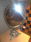 A gilt metal swing mirror with pierced edge on triform stand