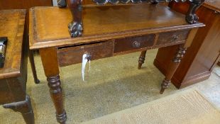A Victorian fruitwood two drawer writing table with leather inset on turned supports