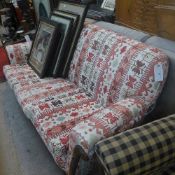 A two seater sofa upholstered in geometric fabric on bun feet