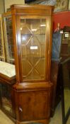 A yewood corner cabinet the glazed panel above cupboard