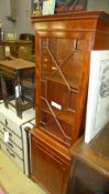 A yewood narrow bookcase the dentil cornice above glazed panel and cupboard