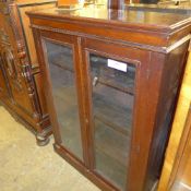 A Victoria walnut dwarf bookcase with glazed panels raised on plinth base