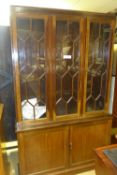 A C20th mahogany bookcase the glazed panels above cupboards on plinth base