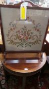 A mahogany demi lune console table and a needlework firescreen